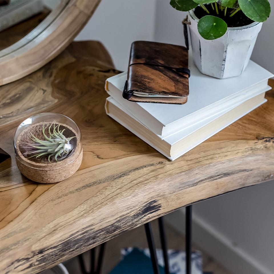 Wooden table with books, wooden wallet, and small plant on a blurred background