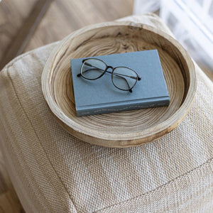 Book with glasses on a wooden tray on a textured surface