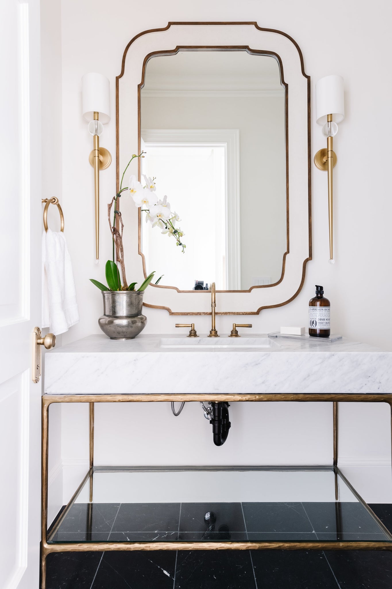 Rockland Wall Sconce 5.25" in aged brass styled in a warmly lit hallway for warm, layered light at Laurie Yapp Home.