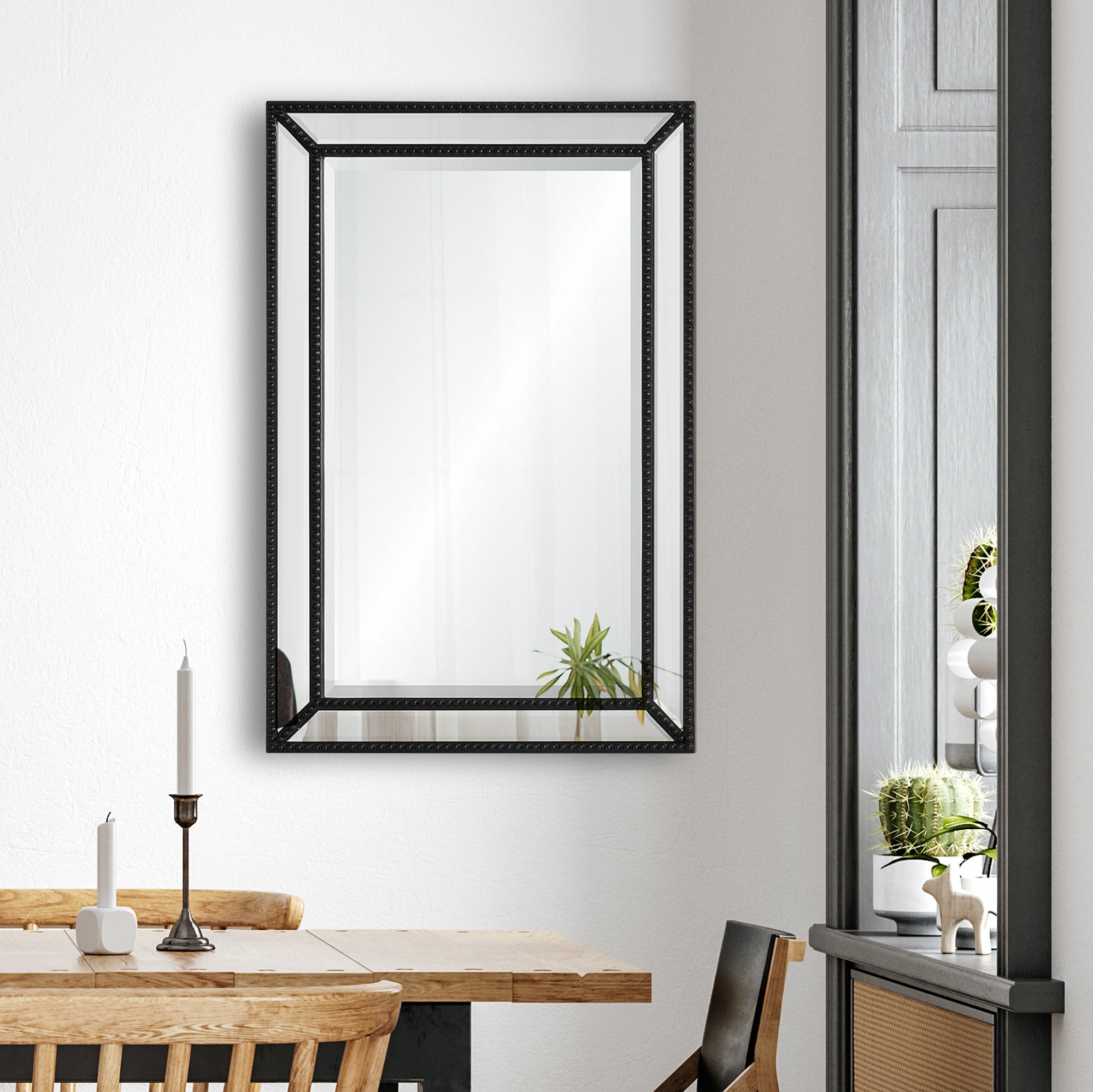 Waterloo Wall Mirror displayed in a dining area, reflecting a plant and candle on a wooden table.