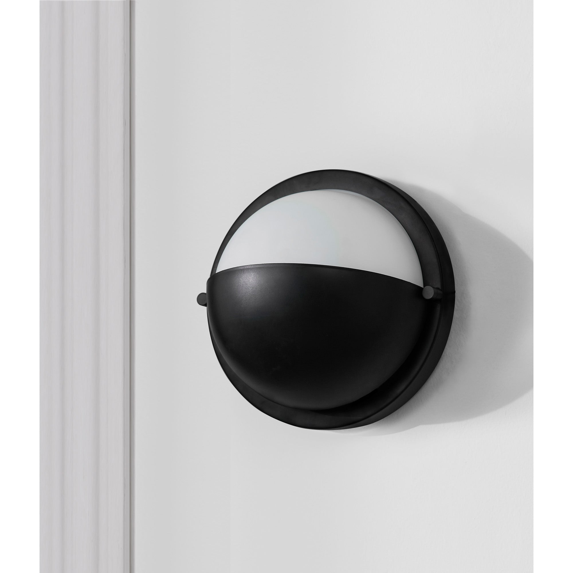 Raina Wall Sconce mounted on a white wall, showcasing its black and white design