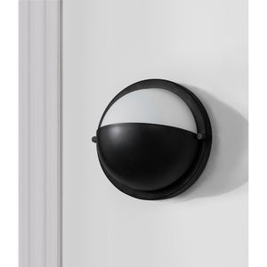 Raina Wall Sconce mounted on a white wall, showcasing its black and white design