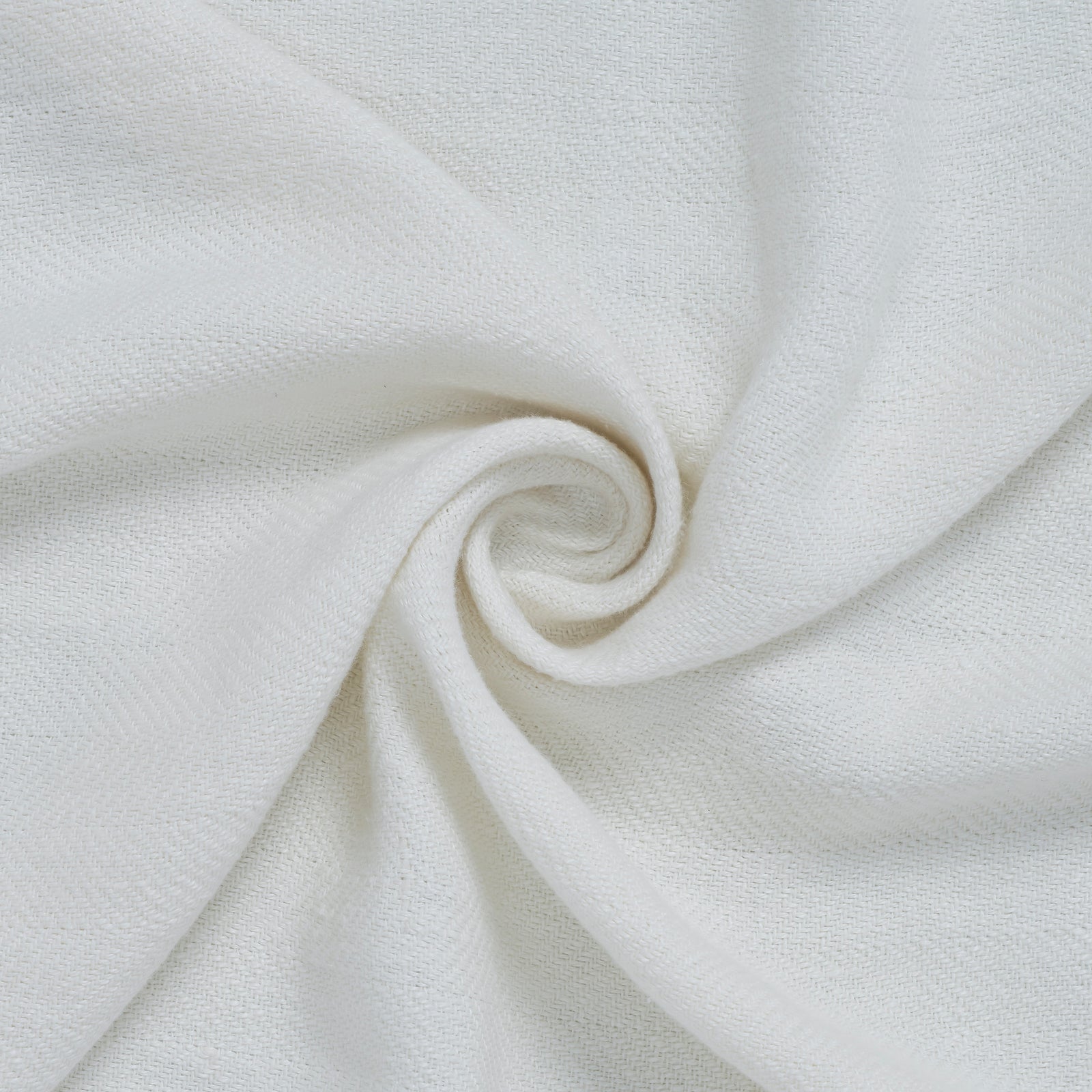 Ragusa Throw in soft white, featuring a textured weave and fringed edges, folded neatly.