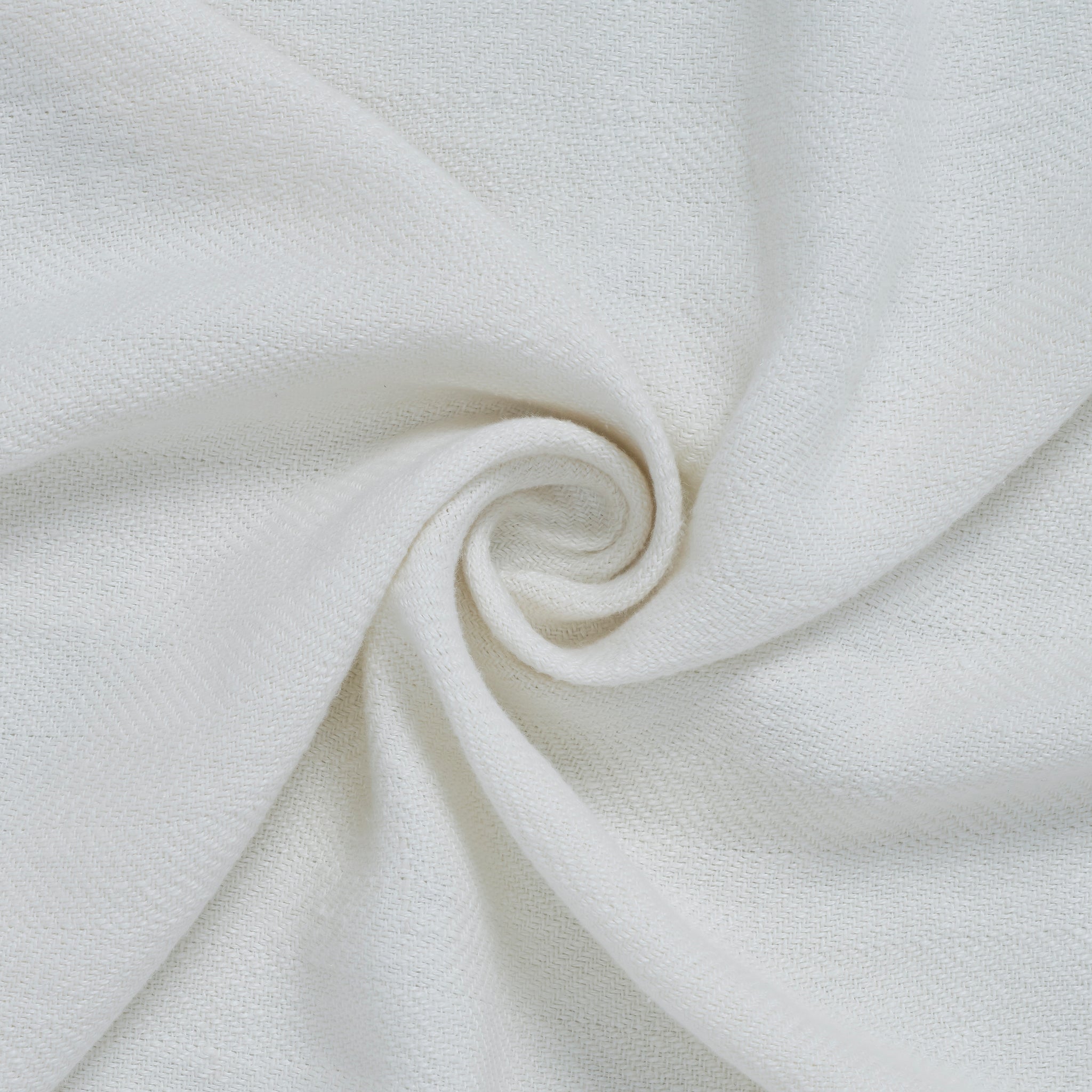 Ragusa Throw in white, showcasing a close-up of the soft fabric in a spiral arrangement.