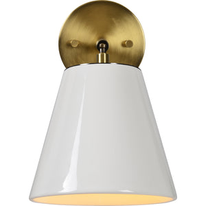 Kai Wall Sconce with white ceramic shade and brass backplate, illuminated from below.