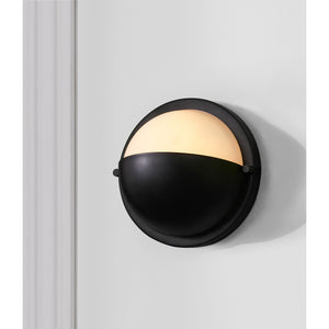 Raina Wall Sconce mounted on a white wall, showcasing its black finish and frosted glass