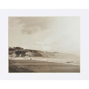 Torreys Wall Art displaying a black and white beach scene with a person walking along the shore, framed.