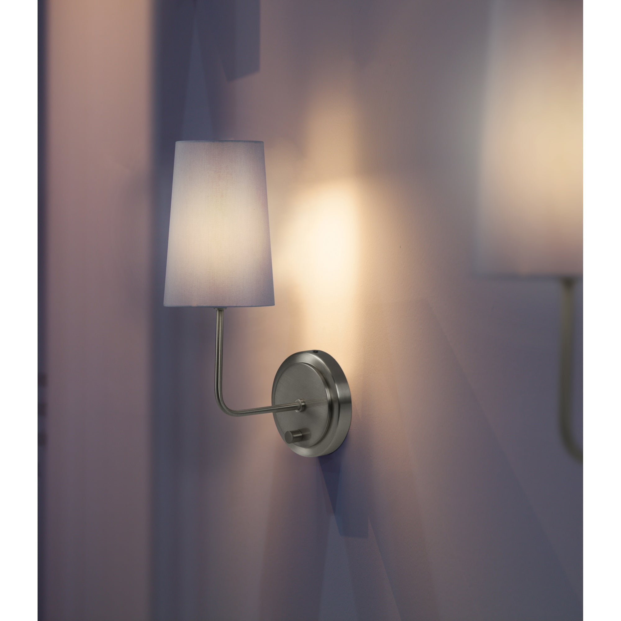 Hydra Wall Sconce featuring a white shade, casting light on a purple wall, with a brushed nickel finish.
