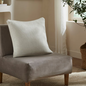 Provence Indoor Pillow placed on a gray chair, showcasing its light blue color and texture.