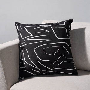 Ray Indoor Pillow on a light sofa, featuring a black fabric with white abstract lines.