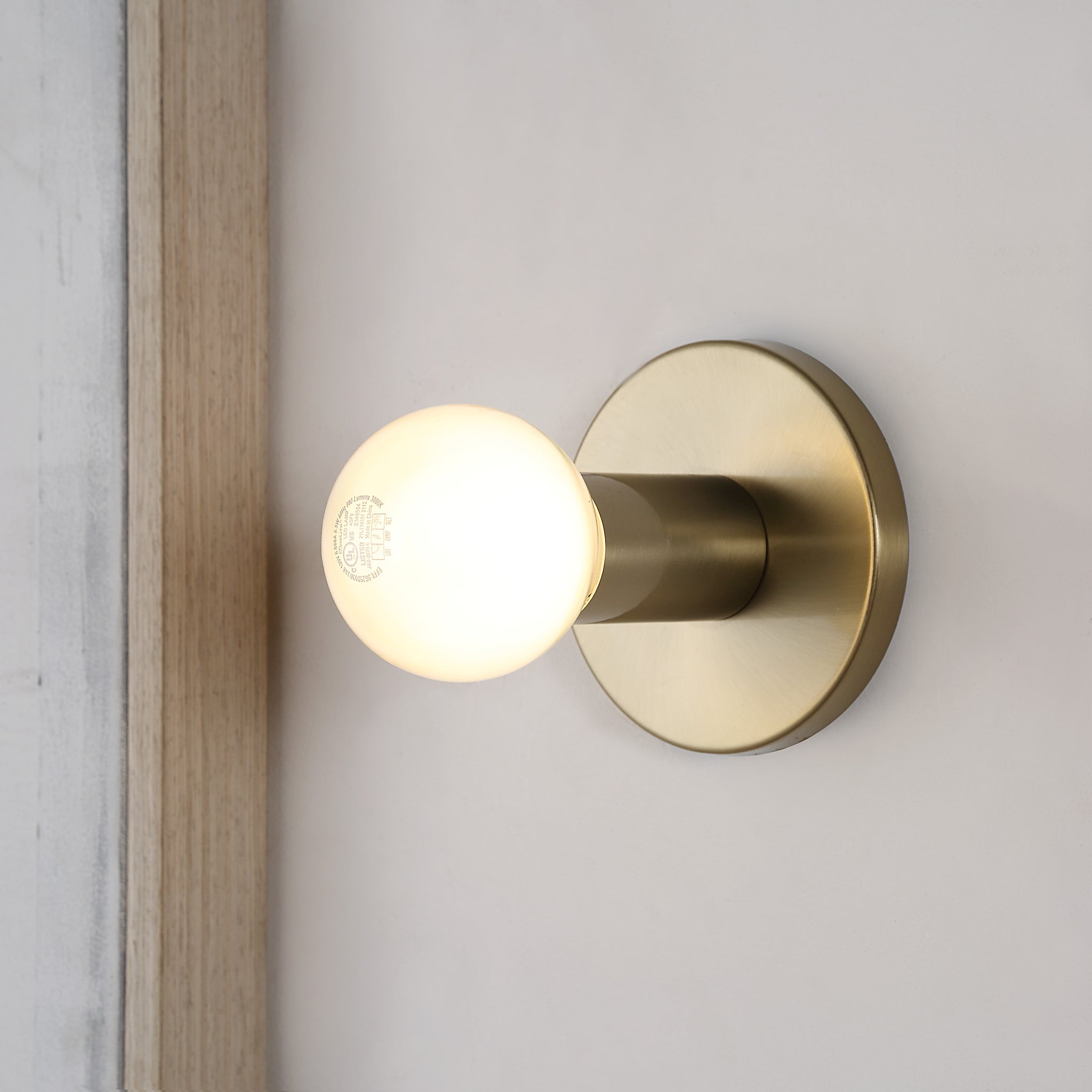 Dania Wall Sconce illuminated with a warm white light, mounted on a wall.