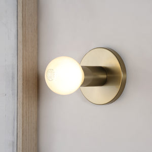 Dania Wall Sconce illuminated with a warm white light, mounted on a wall.