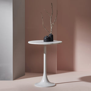 Alina Table styled with black vases on top, set against a pink wall for a modern look.