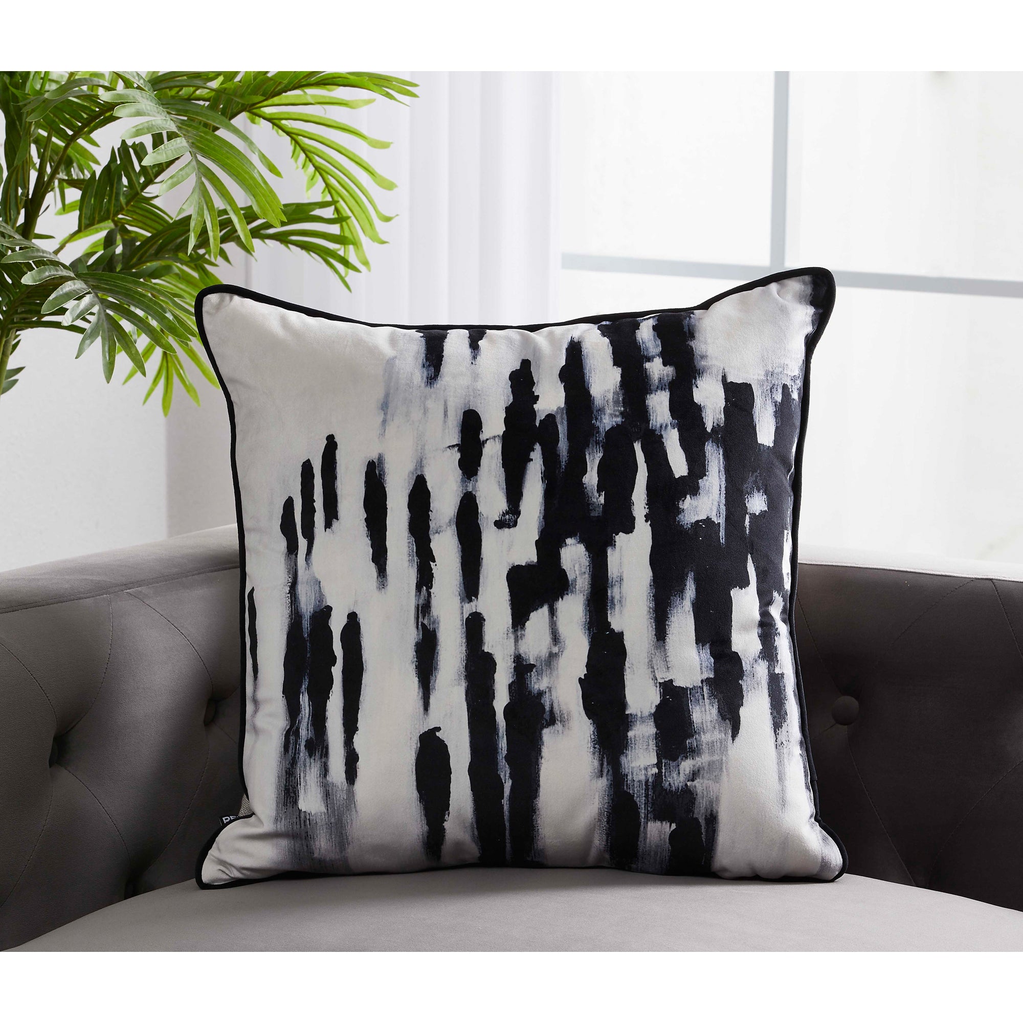 Markat Indoor Pillow with a black and white brushstroke design on a gray sofa.