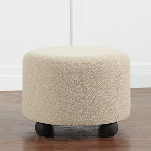 Claude Ottoman in beige, round shape, set against a white wall background