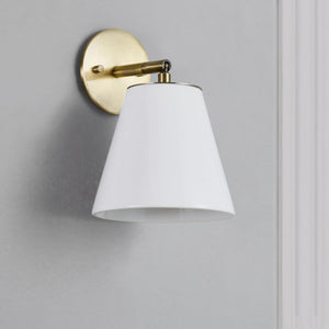 Kai Wall Sconce mounted on a gray wall, showcasing white shade and brass details.