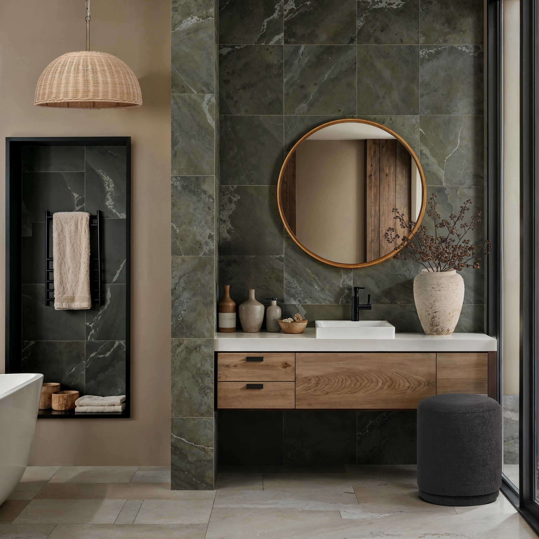 Canna mirror with a round wooden frame above a modern bathroom vanity, featuring green stone tiles and decorative vases.