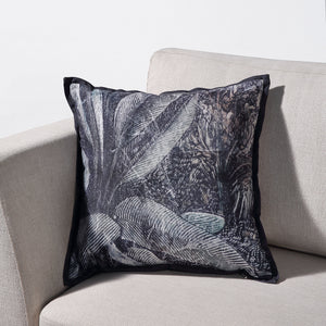 Mangrove Indoor Pillow on a sofa, featuring a lush palm leaf design with a dark border.