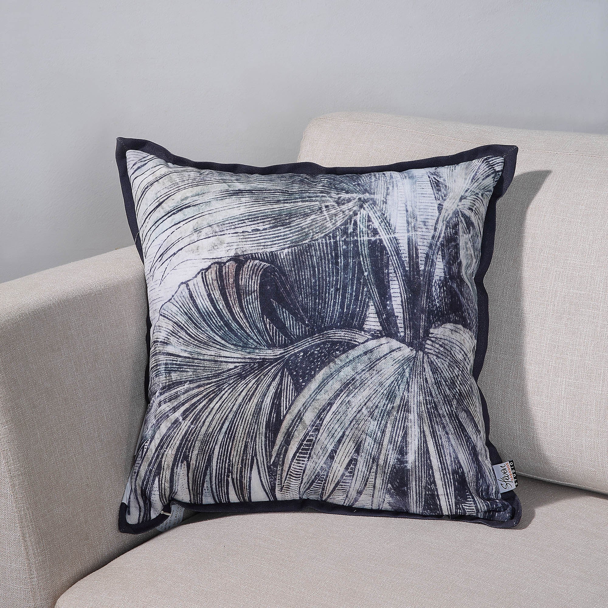 Mangrove Indoor Pillow on a light sofa, showcasing a detailed palm leaf pattern.