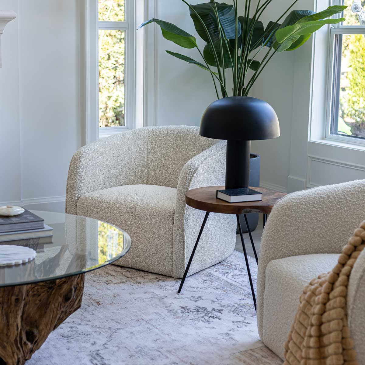Modern living room with beige armchair, glass coffee table, and black lamp.