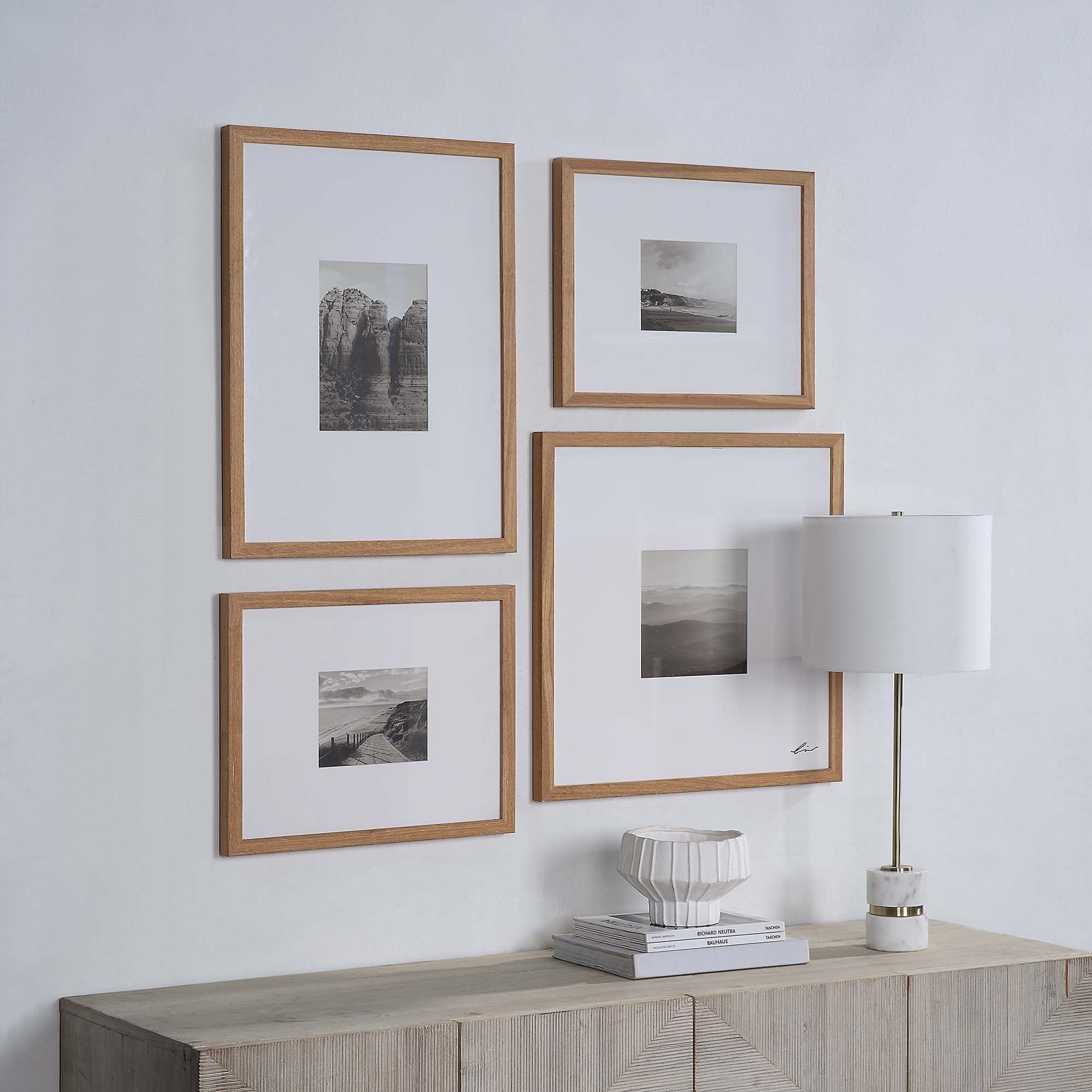Torreys Wall Art arranged on a wall, featuring four black and white images in wooden frames beside a lamp.