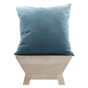 Warrington indoor pillow in blue velvet, displayed on a wooden bench, side view.