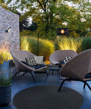 Outdoor seating area featuring Fieldfare Outdoor Pillows on wicker chairs, surrounded by greenery.