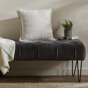 Colmar Indoor Pillow styled on a dark tufted bench with a plant and books.