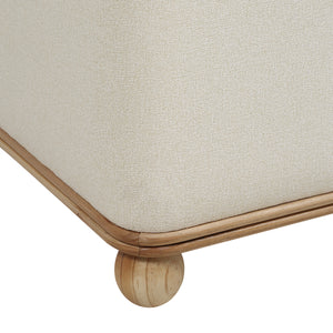 Close-up of Sines Ottoman showing light beige fabric and wooden trim
