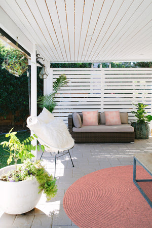 Outdoor setting featuring Morane Outdoor Pillows on a couch, surrounded by plants and decor.
