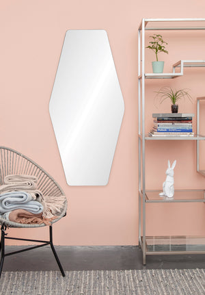 Switzer Wall Mirror mounted on a pink wall next to a modern shelf and chair