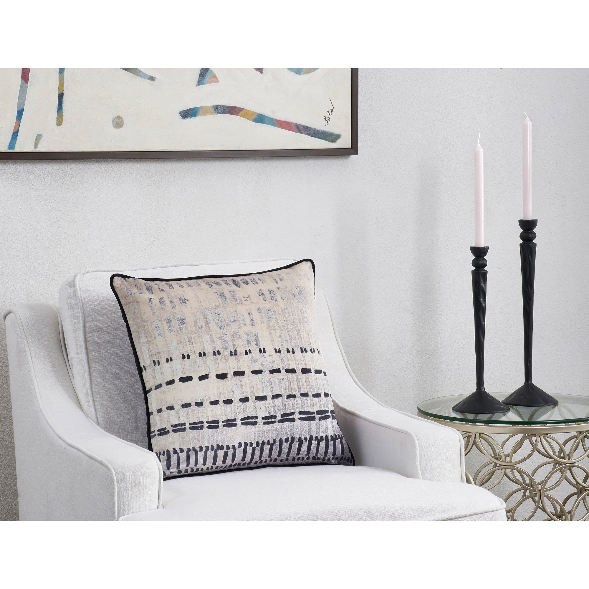 Zitsa Indoor Pillow placed on a white armchair beside black candle holders