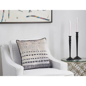 Zitsa Indoor Pillow placed on a white armchair beside black candle holders