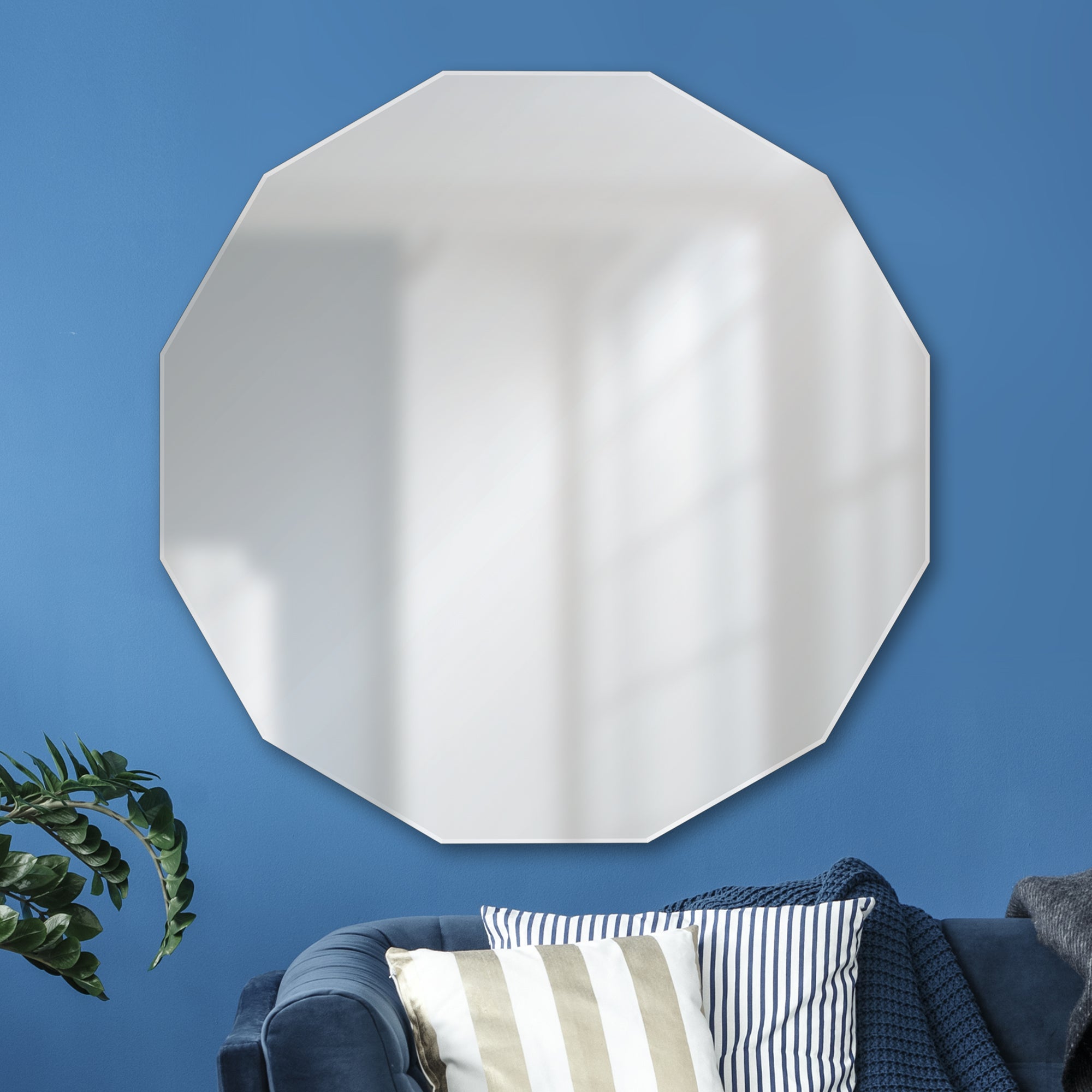 Ovada Wall Mirror displayed on a blue wall above a couch with decorative pillows.