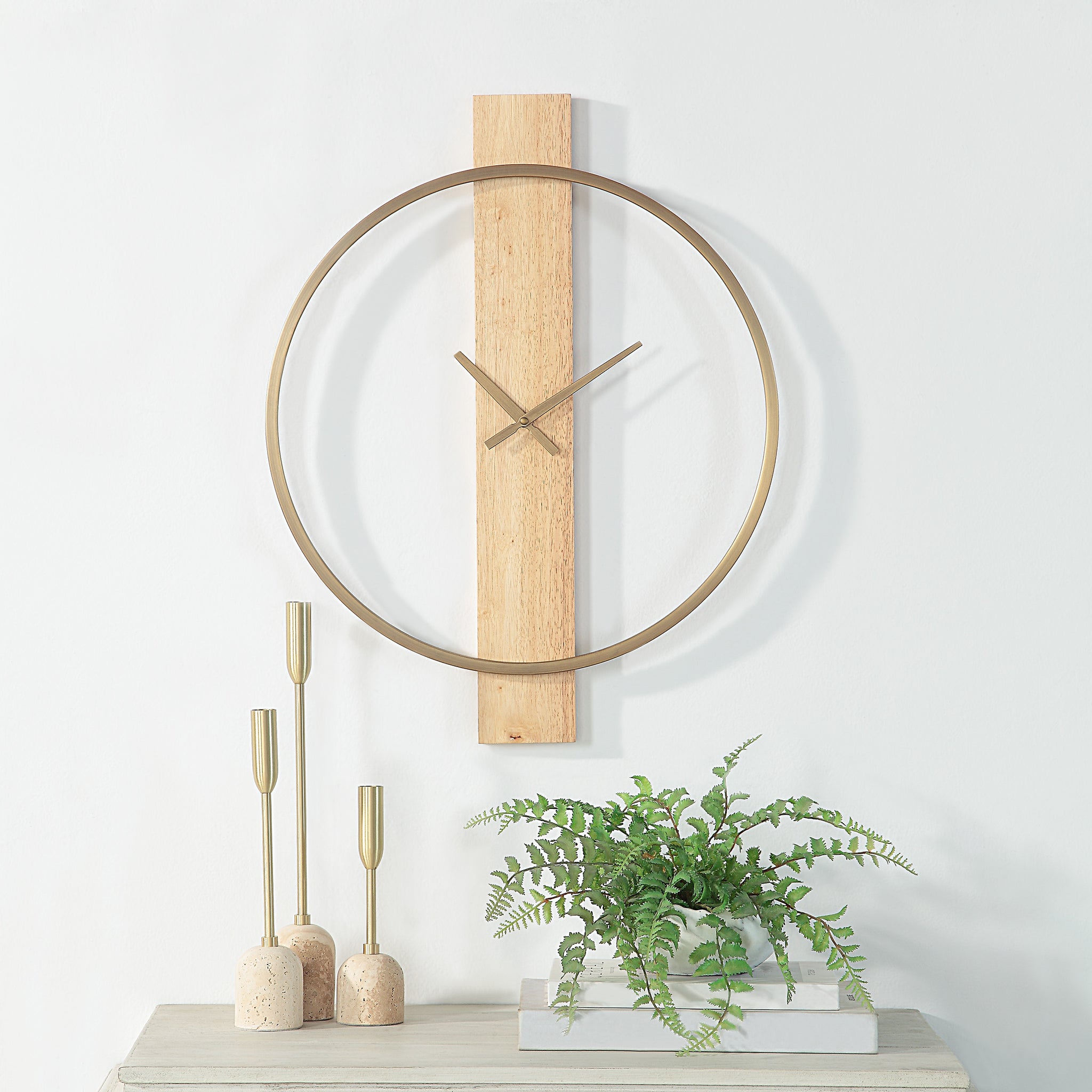 Pollux Wall Clock mounted on a wall with decorative candles and a plant.