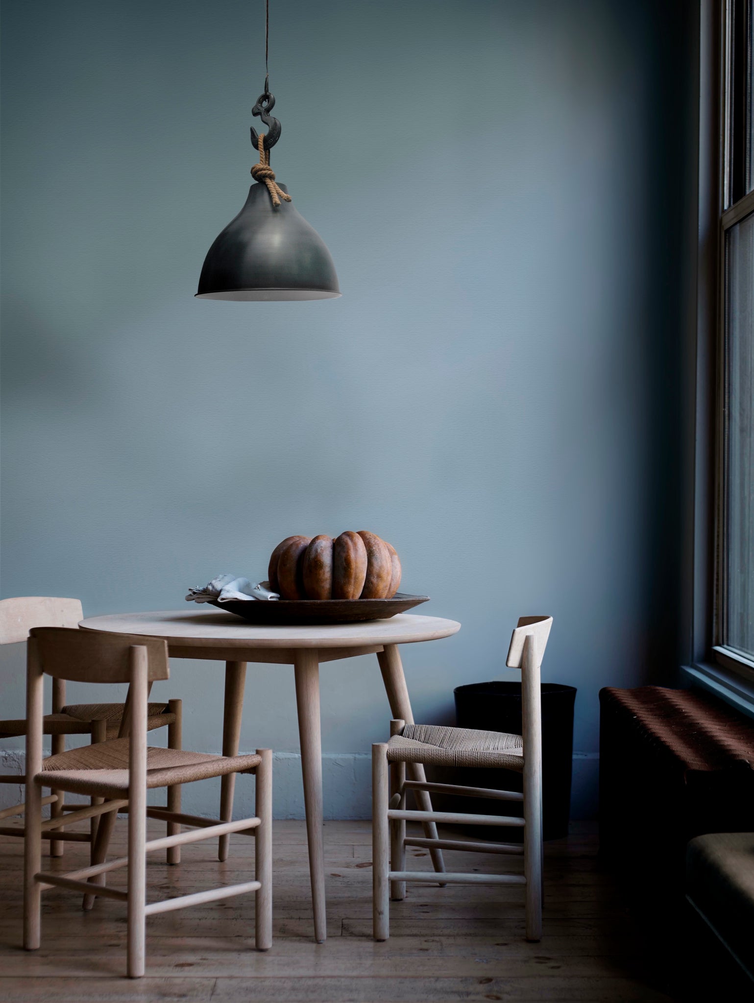 Maturin pendant light above a wooden dining table with chairs, featuring a black metal shade and rope.