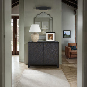 Jean Cabinet in a living space with a lamp, mirror, and framed pictures